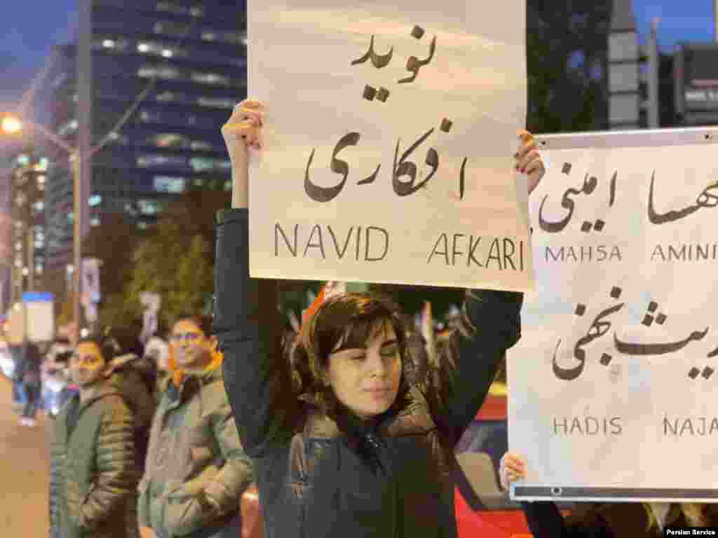 یک زن شرکت کننده پلاکاردی با نام نوید افکاری را حمل می&zwnj;کند تا نام او را یادآور شود.