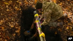 Ukrainian territorial defense deminers put Russian weapons and ammunition in a hole to be destroyed as they clear mines near Hrakove village, Ukraine, Oct. 13, 2022.