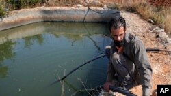 Nazih Sabra sets a tube to pump water from an artificial pond at Harf Beit Hasna village in Dinnieh province, north Lebanon, Sept. 7, 2022.