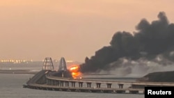 A fire is seen on the Kerch bridge at sunrise in the Kerch Strait, near Russia-annexed Crimea, Oct. 8, 2022.