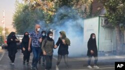 FILE - In this Oct. 1, 2022, photo taken by an individual not employed by the Associated Press and obtained by the AP outside Iran, tear gas is fired by security to disperse protestors in front of the Tehran University, Iran. 