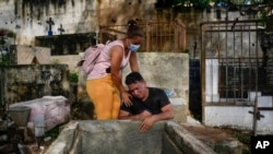 Johaniet Cartaya, a la izquierda, y su hermano Jorge Cartaya lloran después de enterrar en la misma tumba a su madre, Yanet Rivas, y a su tía Aimara Navas en Las Tejerías, Venezuela, el miércoles 12 de octubre de 2022. 