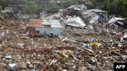 An aerial view shows residents walking past destroyed houses in the village of Pilar, Abuyog town, Leyte province, Philippines on April 14, 2022, at the height of tropical Storm Megi.