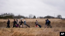 People walk with their belongings, as they flee Ukraine, at the border crossing in Medyka, Poland, March 5, 2022. 