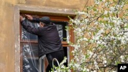 A man puts plastic covers on a window of an apartment building following night shelling in Kramatorsk, Ukraine, Monday, April 18, 2022.