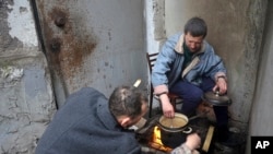 Mariupol residents cook sitting at an entrance to their damaged apartment building in an area of the city that Russian-backed separatists claim to control in the Ukraine city of Mariupol, April 13, 2022.