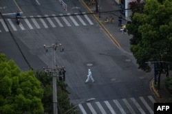 A worker wearing personal protective equipment walks on a street during a COVID-19 lockdown in the Jing'an district in Shanghai, April 12, 2022.
