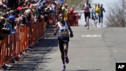 Evans Chebet of Kenya leads the pack of elite runners on his way to win the men's division of the Boston Marathon, April 18, 2022