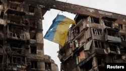 A view shows a torn flag of Ukraine hung on a wire in front an apartment building destroyed during Ukraine-Russia conflict in the southern port city of Mariupol, Ukraine April 14, 2022. (REUTERS/Alexander Ermochenko)
