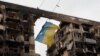 Bendera Ukraina digantung di kawat di depan gedung apartemen yang hancur selama konflik Ukraina-Rusia di kota pelabuhan selatan Mariupol, Ukraina, 14 April 2022. (Foto: REUTERS/Alexander Ermochenko)