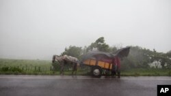 People take cover under a plastic tarp during heavy rain after the San Cristobal volcano spewed smoke and ash, near Chinandega, Nicaragua, Sept. 8, 2012. 