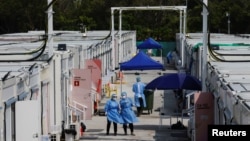 FILE - Workers wearing personal protective equipment work at a COVID-19 isolation facility, amid the pandemic, in Hong Kong, March 21, 2022. 