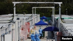 Workers wearing personal protective equipment work at a COVID-19 isolation facility, amid the pandemic, in Hong Kong, March 21, 2022.