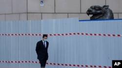 上海一家商场围栏外走过一名戴着口罩的工作人员。（2022年4月20日）