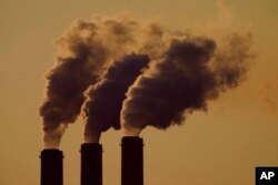 FILE - Emissions rise from the smokestacks at the Jeffrey Energy Center coal power plant as the suns sets, near Emmett, Kan., Sept. 18, 2021.