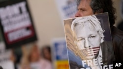 Wikileaks founder Julian Assange supporters hold placards as they gather outside Westminster Magistrates court In London, April 20, 2022.
