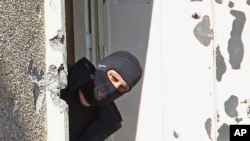 FILE - A masked policeman searches for clues at terrorist Mohamed Merah's apartment building in Toulouse, southern France. 