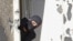 FILE - A masked policeman searches for clues at terrorist Mohamed Merah's apartment building in Toulouse, southern France. 