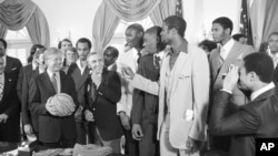 FILE - President Jimmy Carter holds a basketball presented to him by members of the University of Louisville basketball team at the White House in Washington, April 3, 1980.