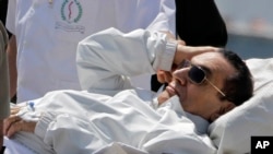 Mantan Presiden Mesir Hosni Mubarak dikawal oleh petugas medis dan tentara saat mendarat dengan helikopter ambulansnya di rumah sakit militer Maadi, seusai mengikuti persidangan di Kairo (13/4).