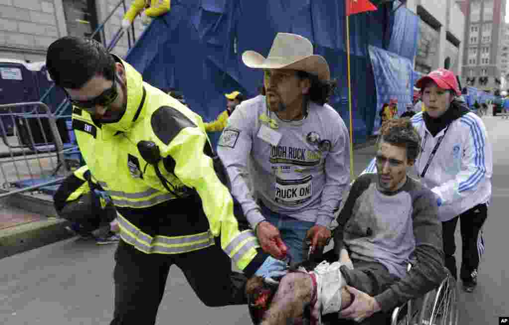 An emergency responder and volunteers, including Carlos Arredondo in the cowboy hat, push Jeff Bauman in a wheel chair after he was injured in an explosion near the finish line of the Boston Marathon April 15, 2013. 