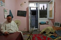 FILE - This photo from Aug. 29, 2009, shows Zebulon Simentov, the last known Jew living in Afghanistan, at his dining room table during Shabbat in his Kabul home, as Shirgul Amiri, right, a local Muslim friend, prays toward Mecca.