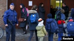 FILE - A Belgian police officer stands guard outside a school in central Brussels, Nov. 25, 2015. 