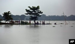 Warga desa terdampak banjir, bertahan di jalanan yang terkepung banjir di desa Burha Burhi, timur Gauhati, India, 15 Juli 2019.
