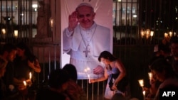Jemaat meletakkan lilin yang menyala di dekat foto Paus Fransiskus selama acara doa bersama untuk kesehatannya di Buenos Aires pada 7 Maret 2025. (Foto: AFP)