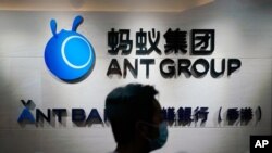In this Oct. 23, 2020, photo, an employee walks past a logo of the Ant Group at their office in Hong Kong. 