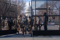 FILE - Members of the National Guard change shifts as they exit through security fencing, Jan. 16, 2021, in Washington as security is increased ahead of the inauguration of Joe Biden as president.