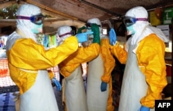 FILE - Health workers, such as these at the Doctors Without Borders Ebola treatment center in Conakry, Guinea, provide vital but risky care for patients.