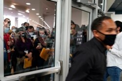 Election challengers, left, wait outside after an election official, right, closed the door to the central counting board, November 4, 2020, in Detroit.
