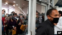 Election challengers, left, wait outside after an election official, right, closed the door to the central counting board, Nov. 4, 2020, in Detroit.