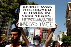 An anti-government protester holds a placard during a protest marking the first anniversary of the massive blast at Beirut's port, near Parliament Square, in Beirut, Lebanon, Aug. 4, 2021.