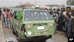 People surround a minibus struck in apparent explosion near highway overpass in Kaduna, Nigeria, Feb. 7, 2012.