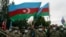 FILE - Azerbaijani soldiers wave national flags after the transfer of the Lachin region to Azerbaijani control, part of a peace deal requiring Armenia to cede Azerbaijani territories it held outside Nagorno-Karabakh, Dec. 1, 2020.