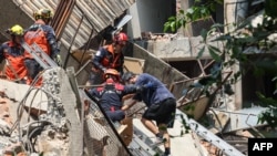 This photo taken by Taiwan's Central News Agency (CNA) on April 3, 2024 shows emergency workers assisting a survivor after he was rescued from a damaged building in New Taipei City, after a major earthquake hit Taiwan's east.