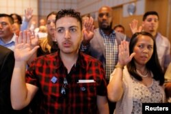 FILE - Applicants take the oath to become new U.S. citizens during a ceremony at the John F. Kennedy Presidential Library in Boston, Mass., July 18, 2018.