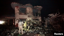 Iraqi security forces inspect the site of a suicide truck bomb attack, at a gas station in the city of Hilla, south of Baghdad, Iraq, Nov. 24, 2016.