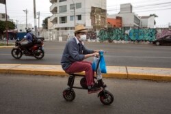 FILE - In this April 11, 2020, file photo, a man wearing a protective face mask as a precaution against the new coronavirus, rides on an electric bike in Lima, Peru. Cycling activists from Germany to Peru are trying to use the moment to get more bike lanes, or widen existing ones, even if it is just a temporary measure to make space for commuters on two wheels. (AP Photo/Rodrigo Abd, File)