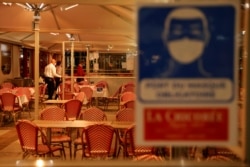 FILE - Waiters are seen inside "La Chicoree" restaurant a few minutes before the start of the late-night curfew introduced as part of coronavirus restrictions, in Lille, France, Oct. 16, 2020.