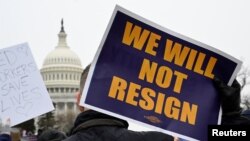 A person displays a sign as labor union activists rally in support of federal workers during a protest, with the U.S. Capitol in the background on Capitol Hill in Washington, Feb. 11, 2025. 