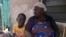 FILE - Funmilayo Kotun, a 66-year-old malaria patient, sits with her grandson Ayomide Kotun outside her house in the Makoko neighborhood of Lagos, Nigeria, on April 20, 2024.