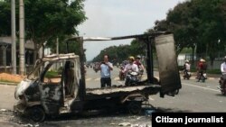 Passersby photograph a burned out vehicle after angry mobs burned and looted scores of foreign-owned factories in Binh Duong province, Vietnam, May 14, 2014. (User generated photo for VOA)
