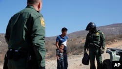 FILE - A Guatemalan father and son, who crossed the U.S.-Mexico border illegally, are apprehended by U.S. Border Patrol agents in San Diego, California, June 28, 2018.