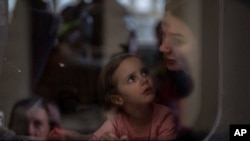A girl looks at her mother on a train bound for Poland in Lviv, western Ukraine, as they flee the war, April 15, 2022.
