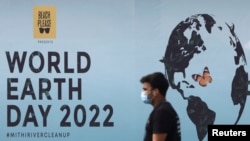 Un hombre pasa junto a un cartel, durante una campaña de limpieza de playas el día de la Tierra, en Mumbai, India, el 22 de abril de 2022.