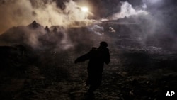 Migrants run as tear gas is thrown by U.S. Border Protection officers to the Mexican side of the border fence after they climbed the fence to get to San Diego, Calif., from Tijuana, Mexico, Jan. 1, 2019. 