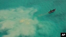 FILE - In this photo provided by the Philippine Coast Guard, a Chinese service boat searches for giant clams in the Scarborough Shoal, in the disputed South China Sea, on April 22, 2019. Five nations held joint maritime exercises in the sea on Sept. 28, 2024.
